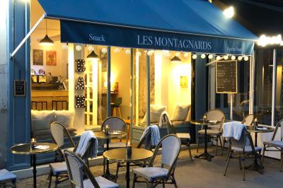 Intérieur d'un café cosy avec comptoir, tabourets, tables en bois et décorations murales variées.