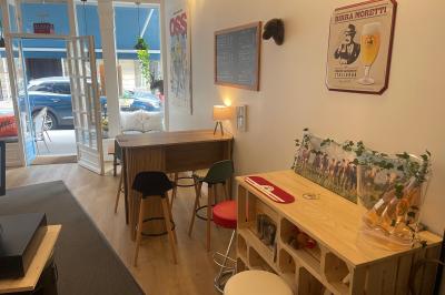 Intérieur d'un café cosy avec comptoir, tabourets, tables en bois et décorations murales variées.