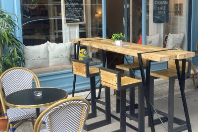 Intérieur d'un café cosy avec comptoir, tabourets, tables en bois et décorations murales variées.