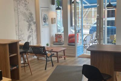 Intérieur d'un café cosy avec comptoir, tabourets, tables en bois et décorations murales variées.