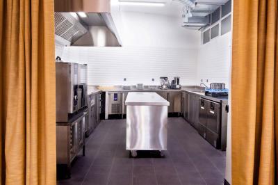 Homme portant une chemise blanche et une médaille, debout dans un environnement intérieur lumineux flou.