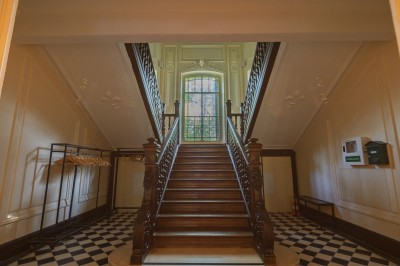 Miniature Escalier d'accès au 1er étage Trois tables hautes recouvertes de housses noires et blanches dans une pièce au parquet en chevrons et murs clairs.