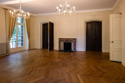 Miniature Salon Le Maitre de Forges Trois tables hautes recouvertes de housses noires et blanches dans une pièce au parquet en chevrons et murs clairs.