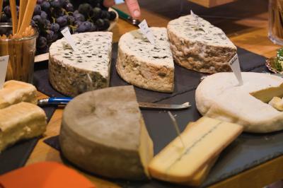 Plateau de fromages variés disposés sur un fond noir, incluant fromages à pâte dure, molle et persillée.