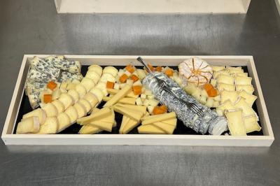 Plateau de fromages variés disposés en rangées, incluant fromages à pâte molle, dure, persillée et chèvre cendré.