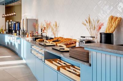 Salle de bain moderne avec douche à l'italienne, lavabo avec miroir éclairé et serviettes pliées sur une étagère.