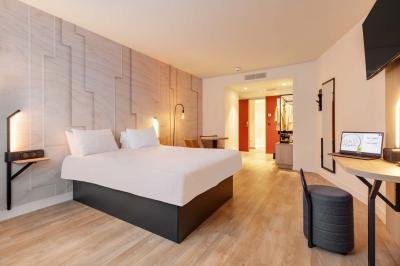 Salle de bain moderne avec douche à l'italienne, lavabo avec miroir éclairé et serviettes pliées sur une étagère.