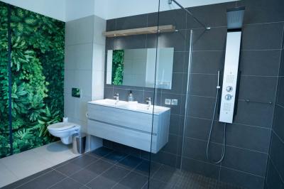 Terrasse en bois avec table, chaises et parasol, entourée de plantes, devant une façade en bois sous un ciel bleu.