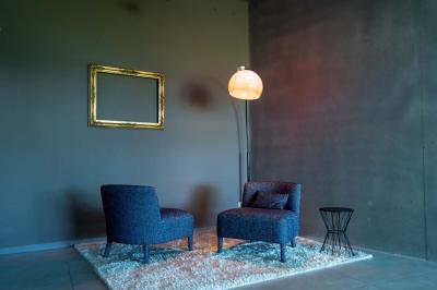 Terrasse en bois avec table, chaises et parasol, entourée de plantes, devant une façade en bois sous un ciel bleu.