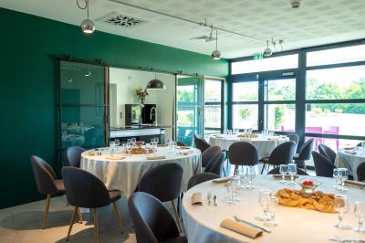 Terrasse en bois avec table, chaises et parasol, entourée de plantes, devant une façade en bois sous un ciel bleu.