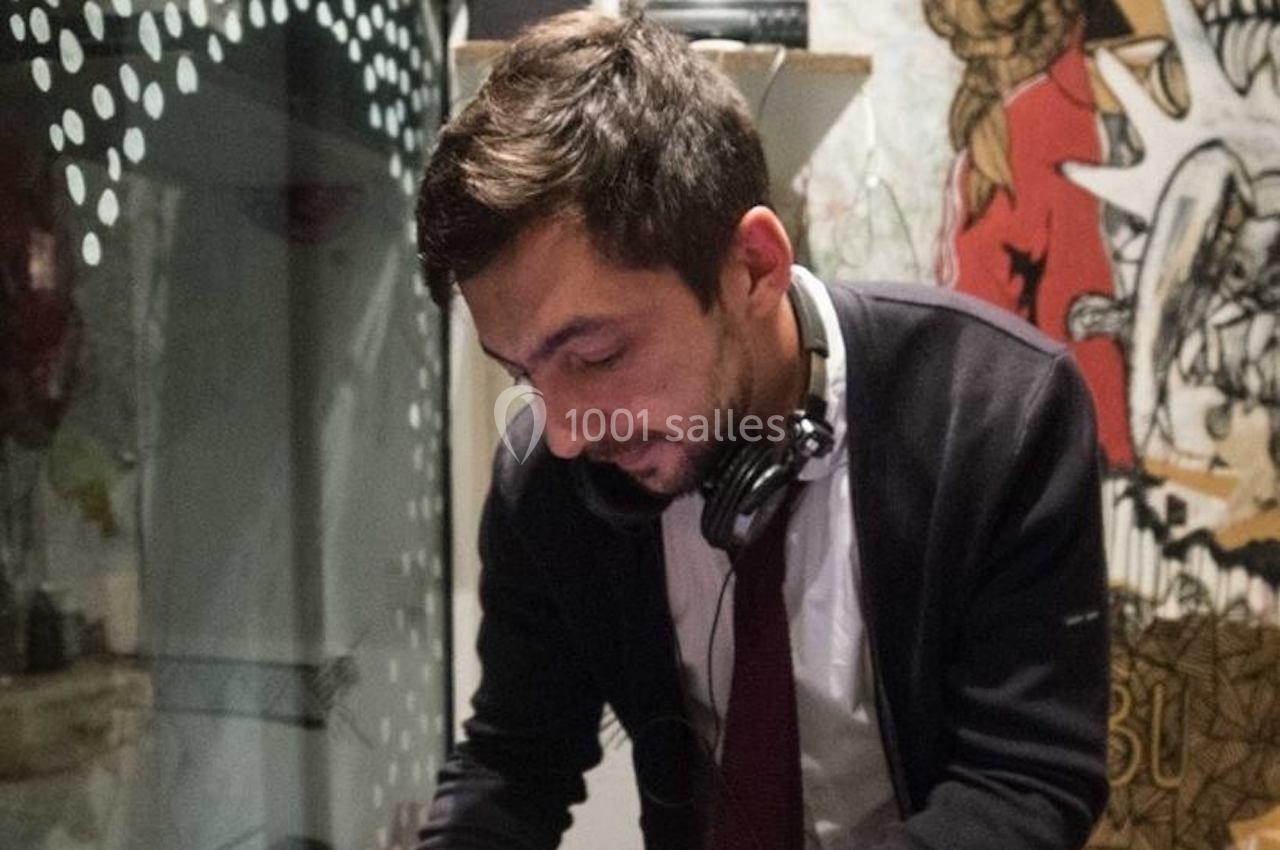 Un homme portant un casque audio autour du cou travaille devant un décor mural artistique.