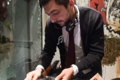 Un homme utilise une platine vinyle dans un espace décoré, avec des disques et des écouteurs autour de lui.