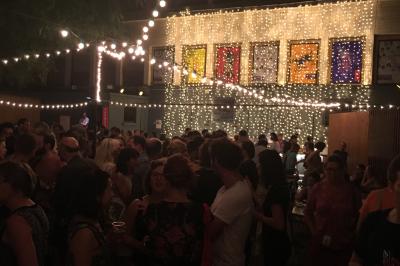 Terrasse couverte avec piste de danse, tables hautes, décoration lumineuse et équipement de DJ au premier plan.