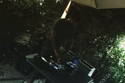 Terrasse couverte avec piste de danse, tables hautes, décoration lumineuse et équipement de DJ au premier plan.