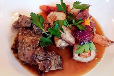 Deux choux farcis servis dans une assiette blanche avec une sauce brune, sur une table en bois.