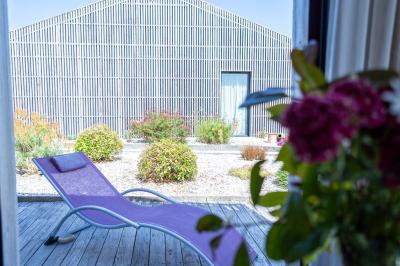 Deux chaises longues en métal avec serviettes roulées dans un espace spa, près d'un sauna en bois.