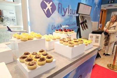 Présentoir de cupcakes variés sur des socles blancs, dans un espace décoré sur le thème de l'aviation.