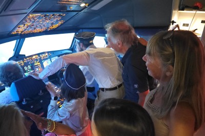 Salle d'exposition avec des stands, des écrans interactifs et des tables hautes, décorée de nuages suspendus.