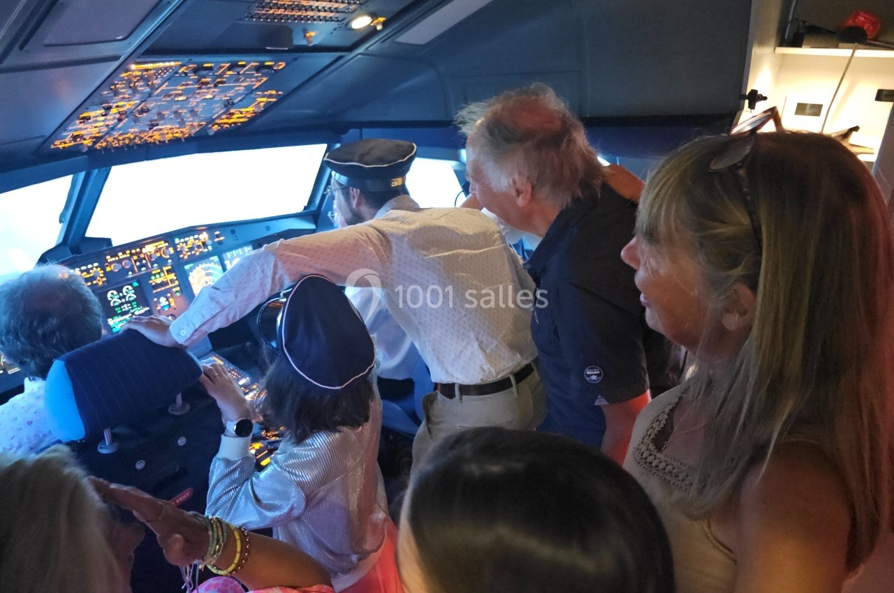 Des personnes, dont un pilote, se tiennent dans le cockpit d'un avion, observant les commandes et l'extérieur.