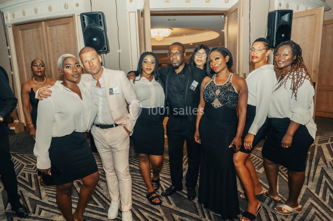 Un groupe de personnes posant dans une salle élégante avec des tenues formelles et un décor intérieur lumineux.
