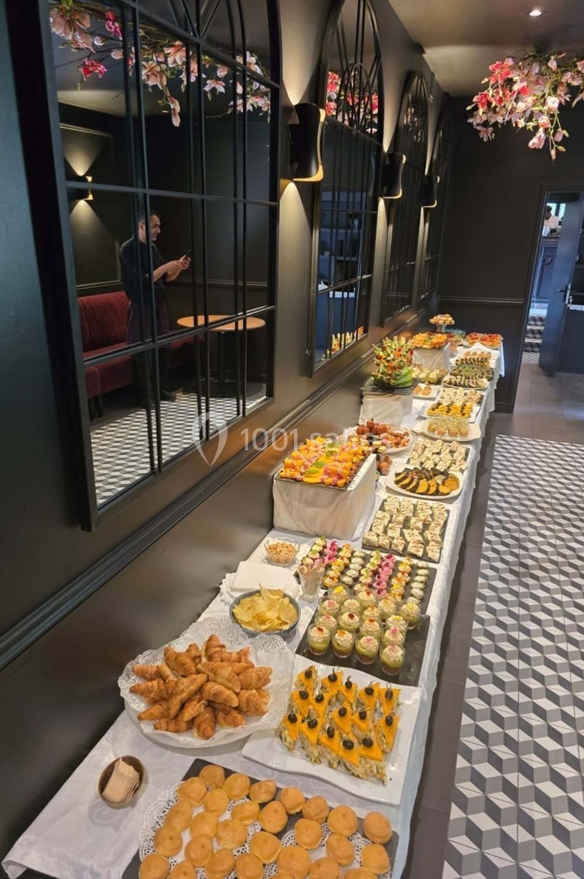 Buffet varié avec viennoiseries, desserts et fruits, disposé sur une longue table dans une salle élégante.