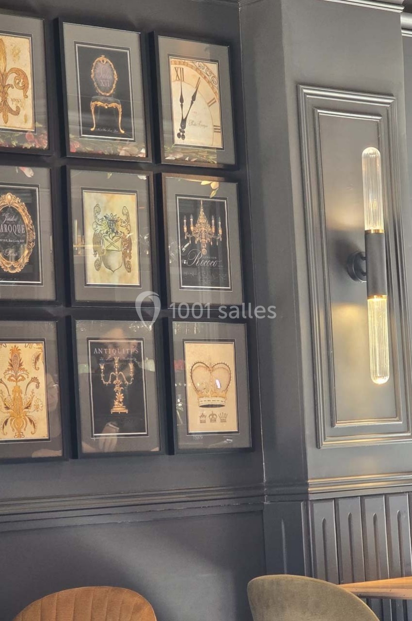 Mur décoré de cadres avec des illustrations variées et un éclairage mural moderne dans un intérieur élégant.