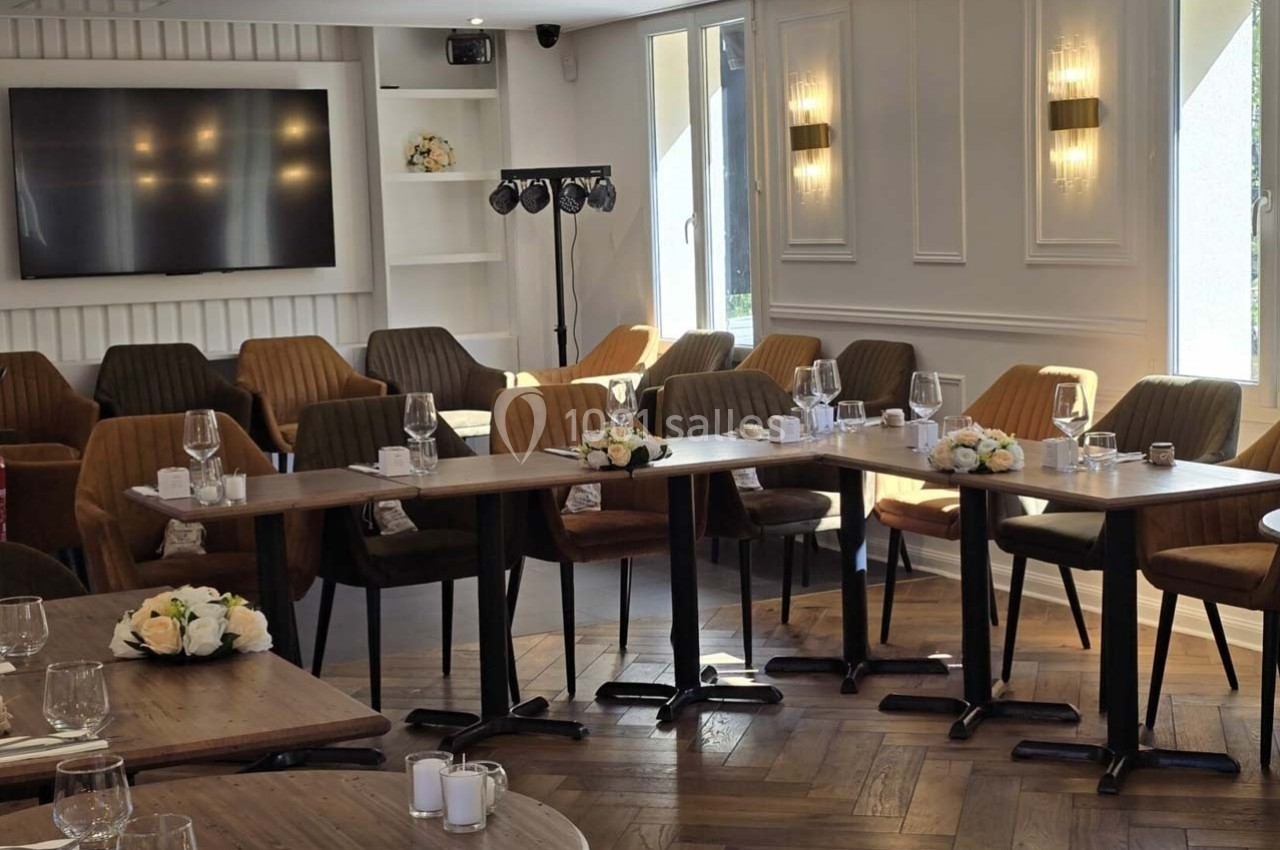 Salle lumineuse aménagée avec des tables en bois, des chaises rembourrées et une décoration florale élégante.
