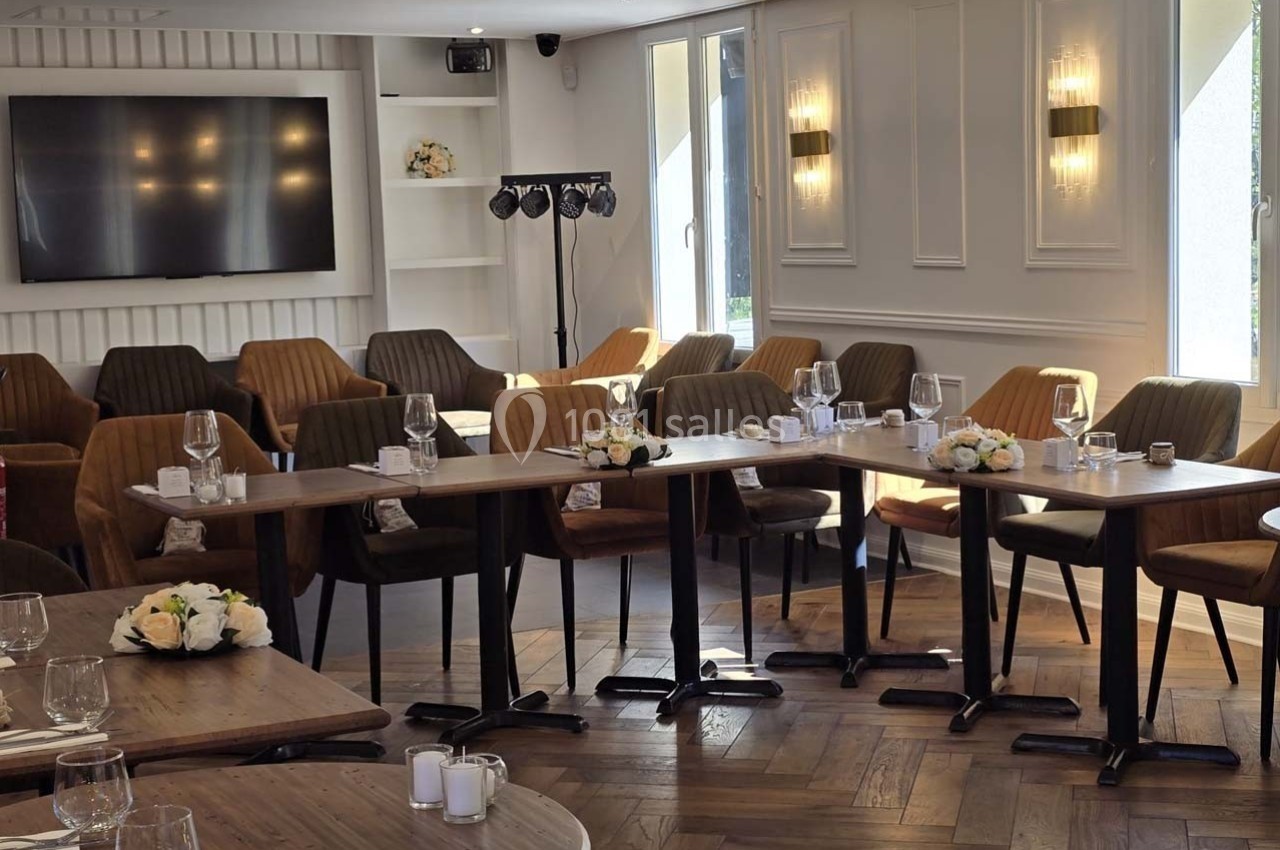 Salle lumineuse aménagée avec des tables en bois, des chaises marron et une décoration florale sobre.