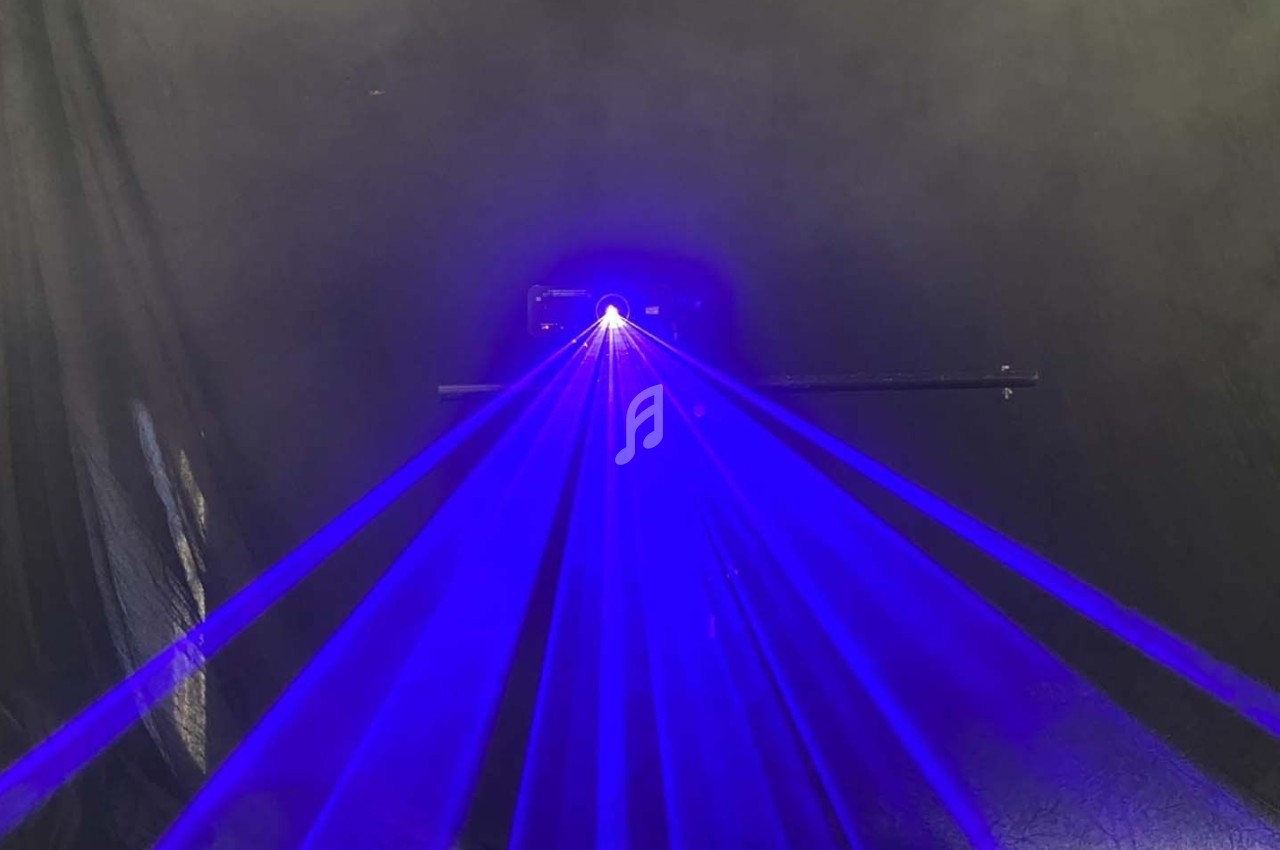Projection de faisceaux lumineux bleus émanant d'un dispositif dans un environnement sombre.