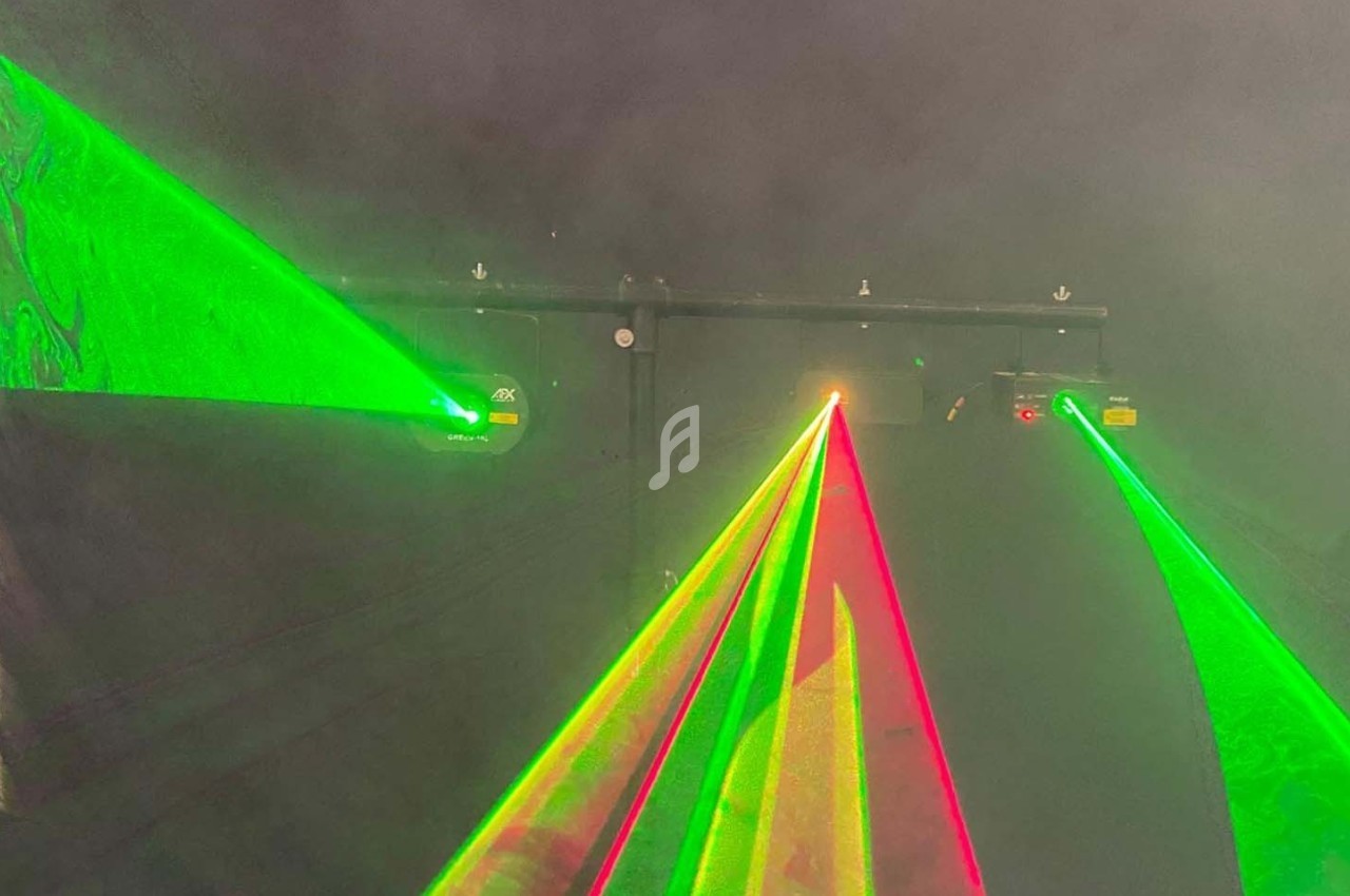 Faisceaux laser verts et rouges projetés dans une ambiance sombre et enfumée.