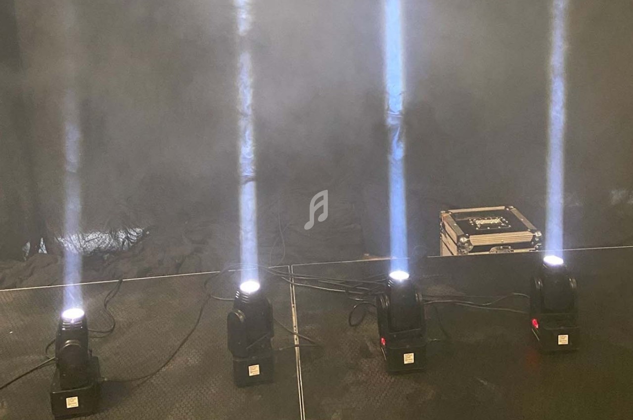 Quatre projecteurs lumineux émettant des faisceaux verticaux dans une ambiance enfumée, avec une valise technique à l…