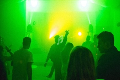 Scène décorée avec des guirlandes lumineuses, éclairages colorés et équipements audio dans une salle vide.