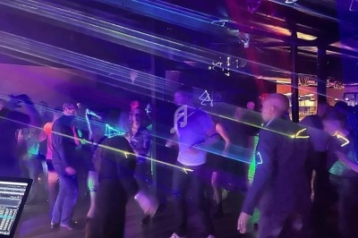 Scène décorée avec des guirlandes lumineuses, éclairages colorés et équipements audio dans une salle vide.