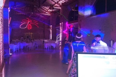 Salle de réception avec éclairages colorés, invités dansant et tables dressées en arrière-plan.