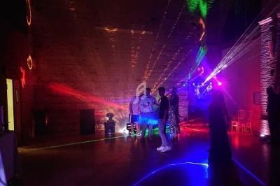 Des personnes discutent dans une salle sombre éclairée par des lumières colorées et des faisceaux laser.