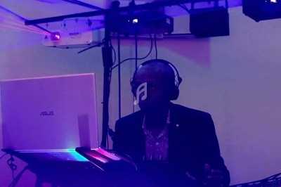 Un DJ portant un casque audio mixe de la musique sur un ordinateur portable dans une ambiance lumineuse tamisée.