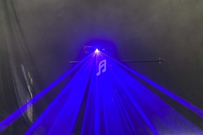 Rayons laser bleus émanant d'un appareil dans un environnement sombre avec un fond noir.