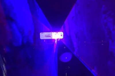 Rayons lumineux violets et bleus se croisant dans un environnement sombre avec un point lumineux central.