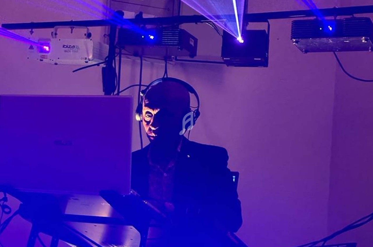 Un DJ mixe de la musique dans une ambiance lumineuse avec des faisceaux laser bleus.