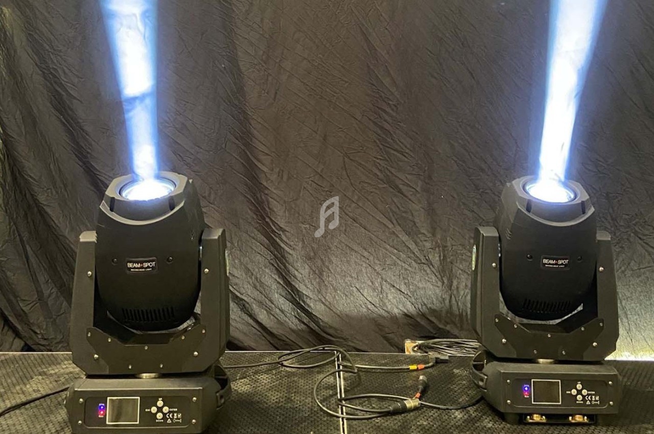 Deux projecteurs de scène émettant des faisceaux lumineux blancs sur un fond noir.