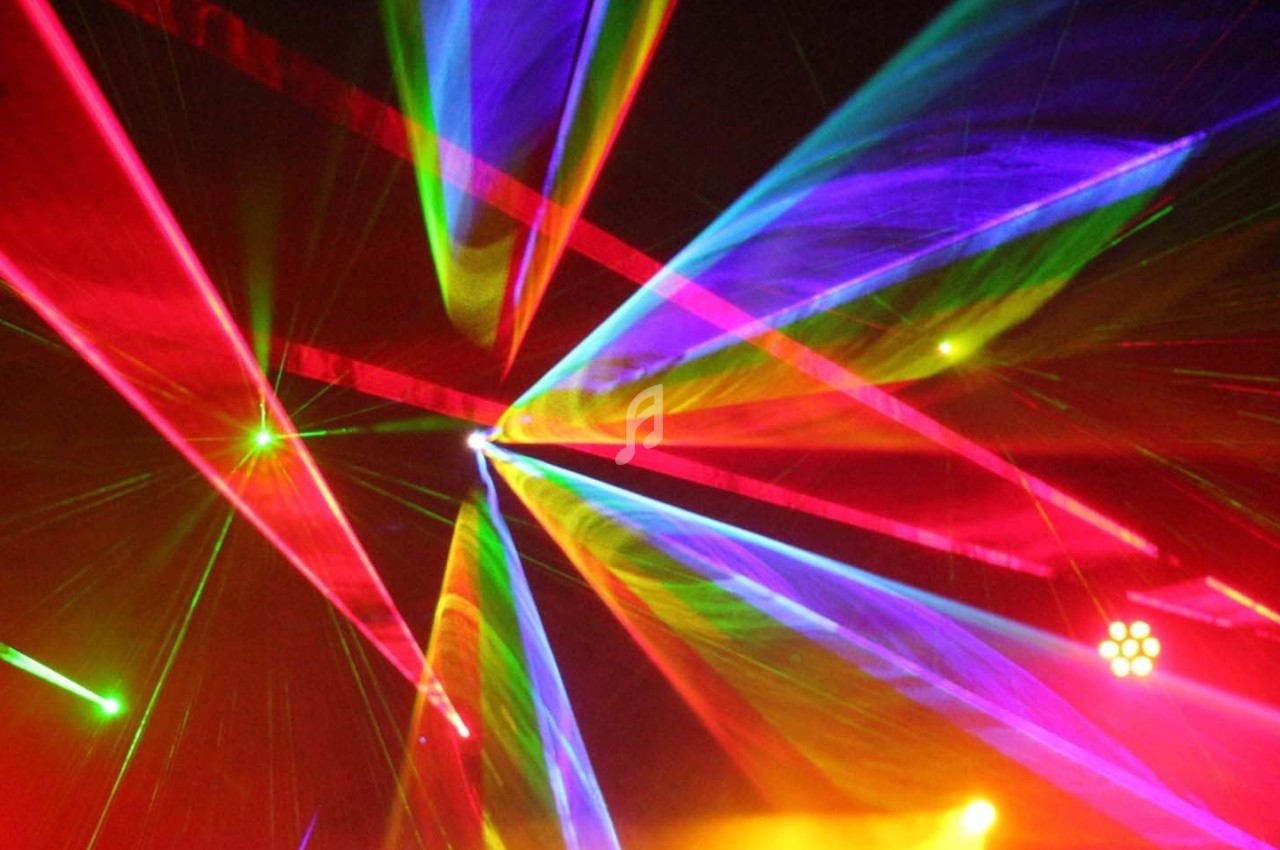 Faisceaux lumineux multicolores traversant une scène sombre, créant un effet visuel dynamique.