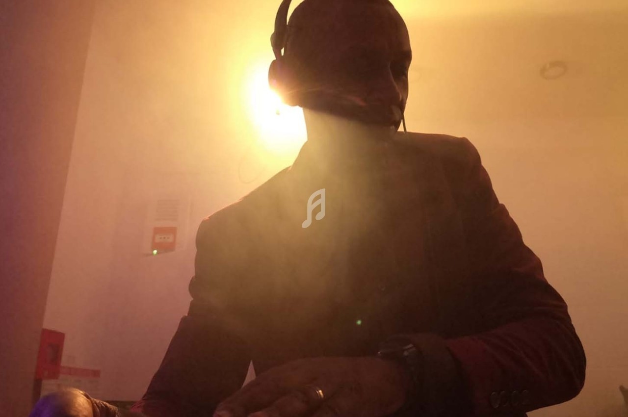 Un homme portant un casque-micro, éclairé par une lumière vive dans une ambiance enfumée.