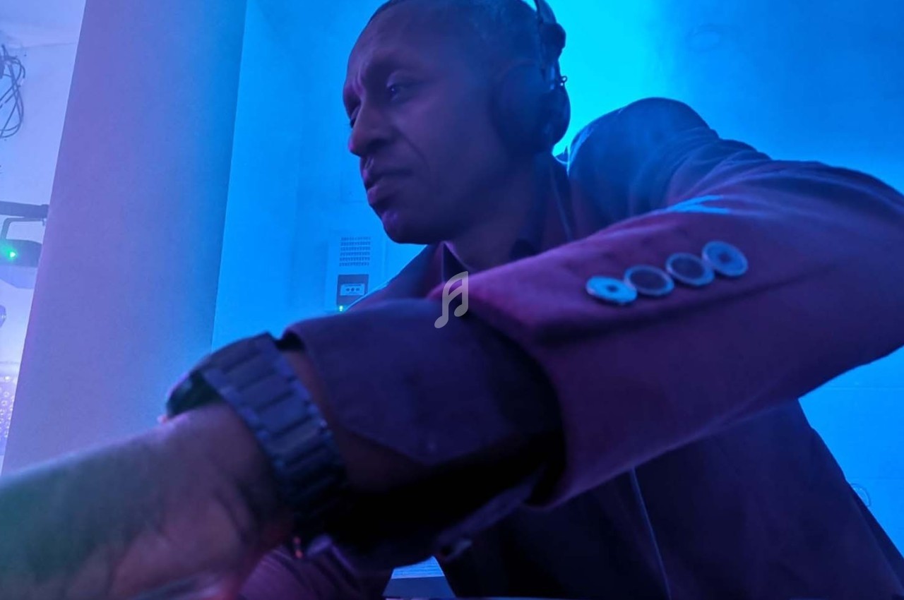 Un DJ concentré mixe de la musique dans une ambiance lumineuse bleutée.