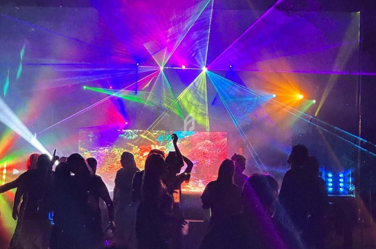 Personnes dansant dans une ambiance festive avec des jeux de lumières colorés et des lasers.
