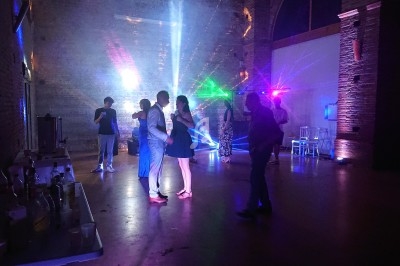 Scène décorée avec guirlandes lumineuses, éclairages colorés et équipements audio dans une salle intérieure.