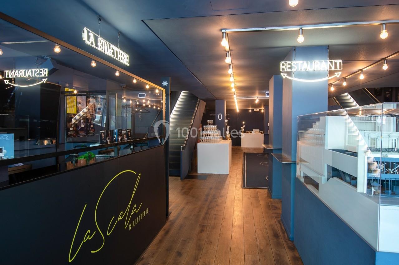 Intérieur d'un restaurant moderne avec un comptoir d'accueil, éclairage suspendu et décoration minimaliste.