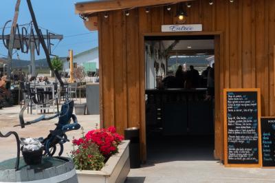 Un couple de dos, debout sur une plage, tenant la main, face à la mer sous un ciel dégagé.