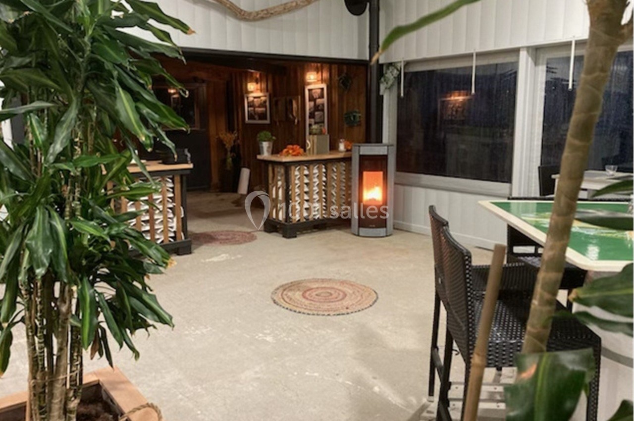 Espace intérieur chaleureux avec poêle à bois, plantes vertes, comptoir en bois et éclairage tamisé.