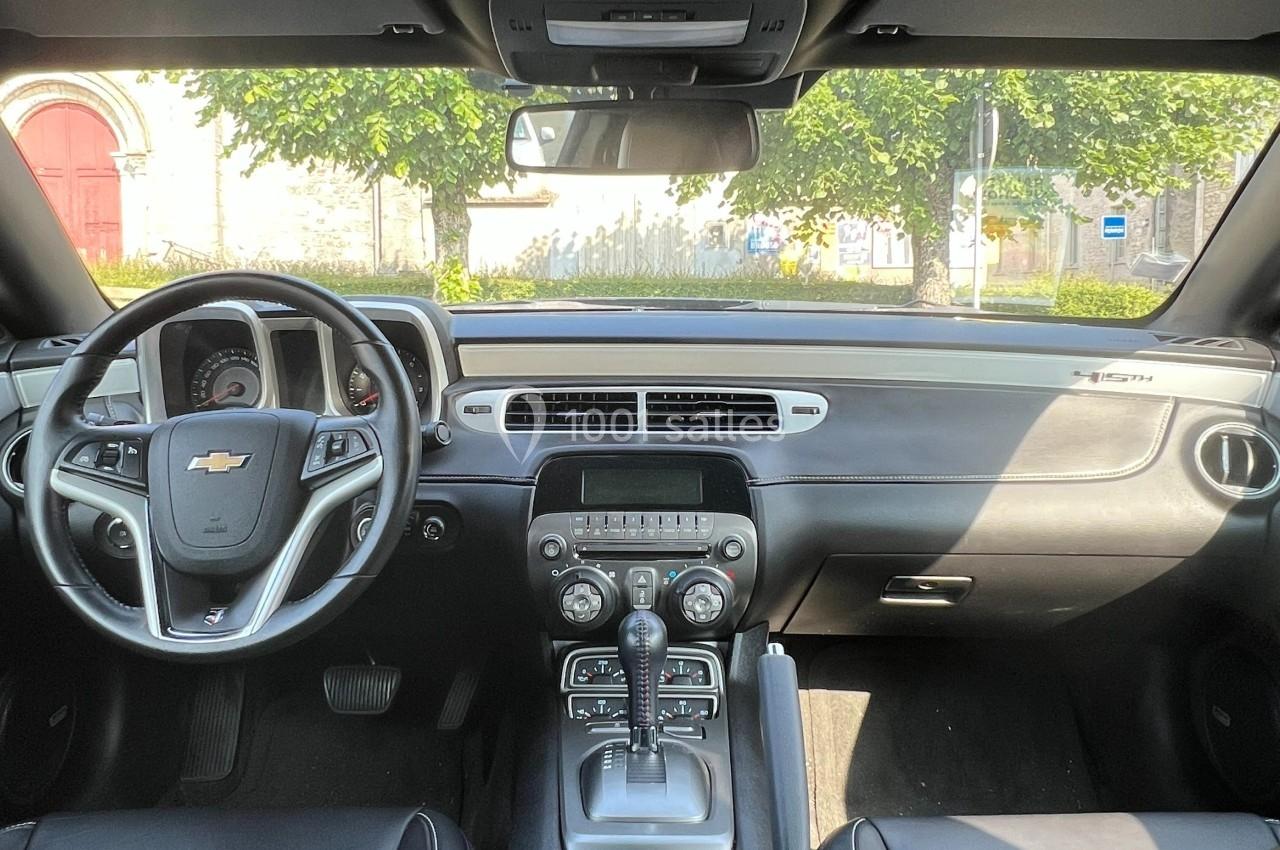 Vue de l'intérieur d'une voiture avec tableau de bord, volant Chevrolet et console centrale sous un éclairage naturel.