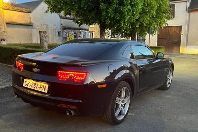 Vue de l'intérieur d'une voiture avec tableau de bord, volant Chevrolet et console centrale sous un éclairage naturel.